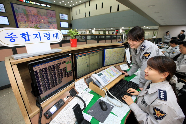 Uniformed police officers on Wednesday monitor the streets from the Seoul Metropolitan Police Agency’s 112 Command Center in Jongno.   KT Corp.