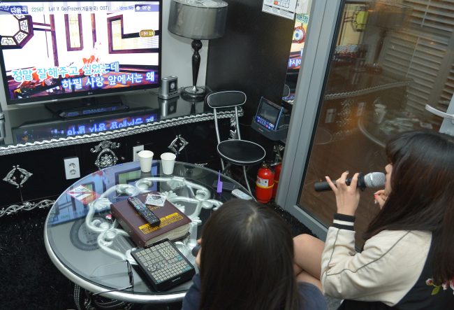 Two women singing inside a Korean noraebang karaoke room in Hongdae, Seoul
