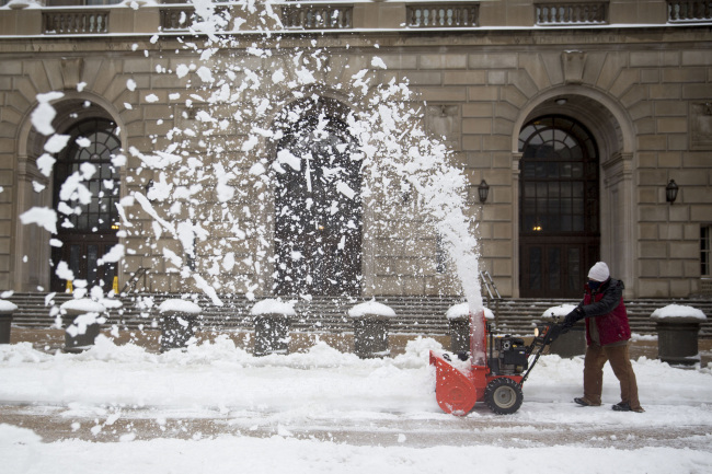 A worker uses a snow blower outside the Internal Revenue Service in Washington, D.C., Thursday.   (Bloomberg)