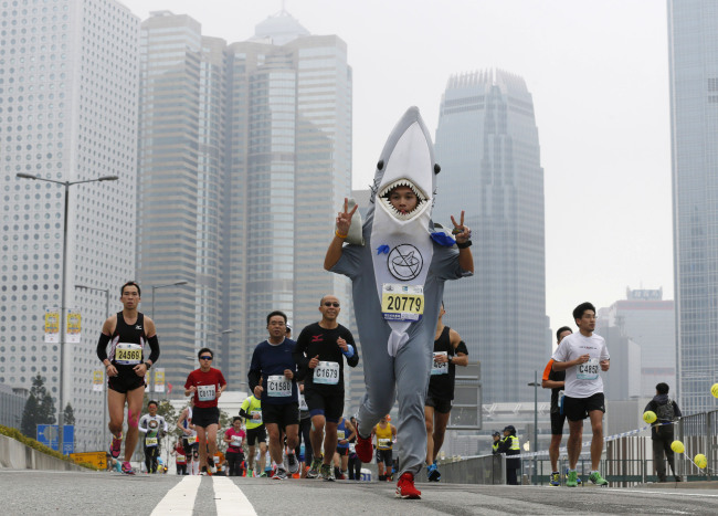 A participant, who urges people to stop eating shark fin, runs wearing a shark outfit, during the Hong Kong Marathon, Sunday.    AP-Yonhap