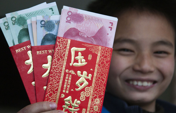 A boy shows the red envelopes he received during Spring Festival this year in Shaoyang, Hunan province.   China Daily