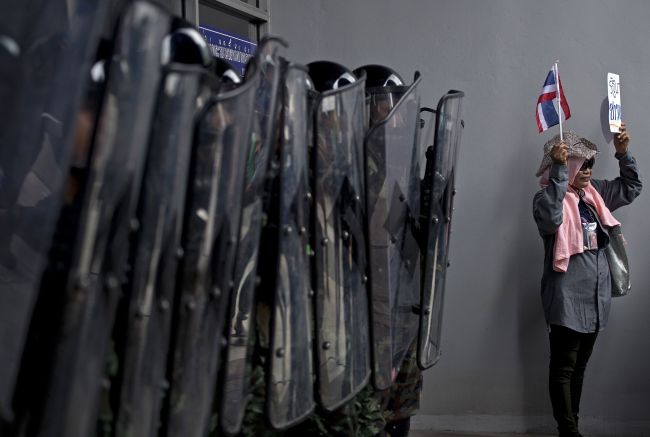 A Thai antigovernment protester stands next to soldiers during a protest against the government’s repeatedly delayed payments for rice submitted to the pledging scheme at the government’s temporary office in Bangkok on Tuesday.   AFP-Yonhap