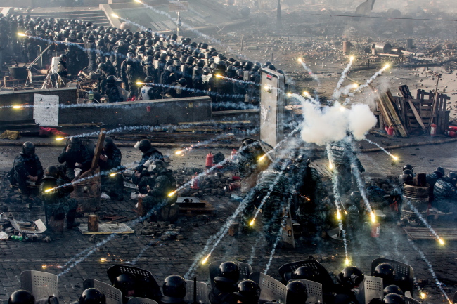 Police take cover behind shields as antigovernment protesters throw flares at them in Kiev’s Independence Square.   ITAR-TASS-Yonhap
Police take cover behind shields as antigovernment protesters throw flares at them in Kiev’s Independence Square.   ITAR-TASS-Yonhap
