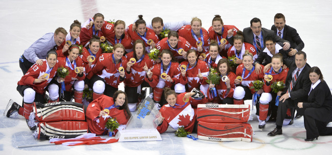 Canadian team poses for photographers after receiving their gold medals during the victory ceremony for women’s ice hockey at the Winter Olympics in Sochi, Russia, Thursday.   UPI-Yonhap