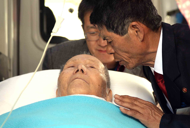 Kim Jin-cheon (right) from North Korea says goodbye to his 90-year-old father Kim Sum-kyung from the South at an ambulance before he leaves Mount Geumgangsan due to health problems on Friday.   Yonhap
