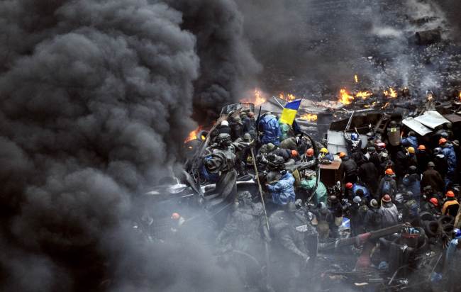 Protesters stand behind burning barricades during a faceoff against police in Kiev on Thursday.    AFP-Yonhap
