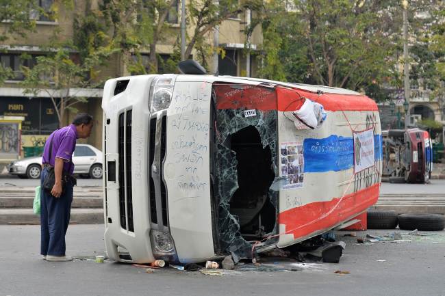 A man looks at a vehicle upturned during recent riots in Bangkok on Saturday.   AFP-Yonhap