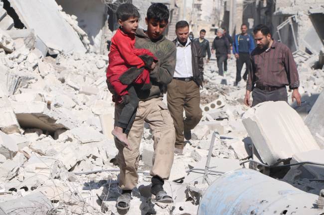 A Syrian man carries a child following an air strike by the government forces in the northern Syrian city of Aleppo on Saturday.   AFP-Yonhap