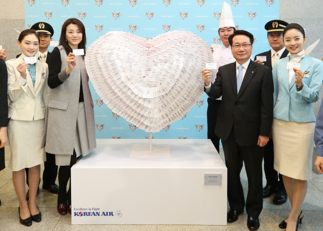 Korean Air CEO Ji Chang-hoon (third from right) and communications chief Cho Hyun-min (third from left) pose with a heart-shaped sculpture made of the business cards of some 1,200 employees during a New Year event at the company’s headquarters in central Seoul on Monday.   Korean Air