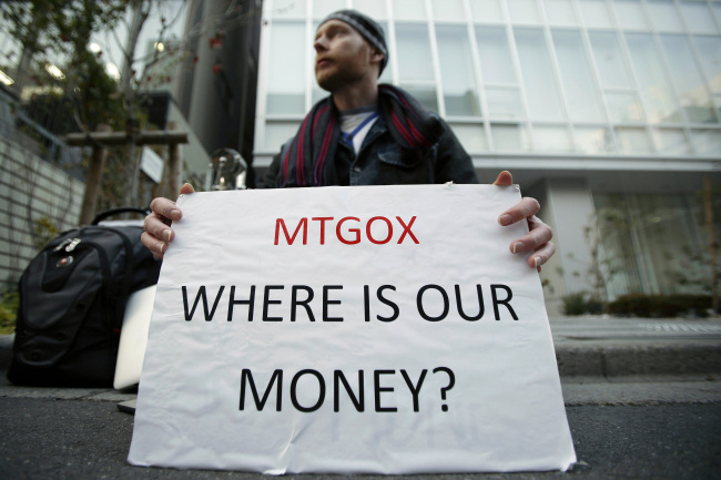 Kolin Burges, a Mt. Gox customer, holds a placard while protesting outside a building housing the headquarters of Mt. Gox and its parent company Tibanne Co. in Tokyo on Tuesday.   Bloomberg