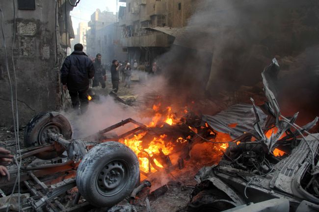 People gather around a burning vehicle following reported shelling by government forces on Bustan al-Qasr neighborhood in the northern Syrian city of Aleppo on Wednesday.   AFP-Yonhap