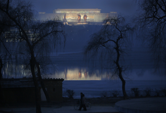 North Koreans walk along the bank of Daedonggang River opposite statues of the late leaders Kim Il-sung and Kim Jong-il at Mansu Hill in Pyongyang, North Korea.   AP-Yonhap