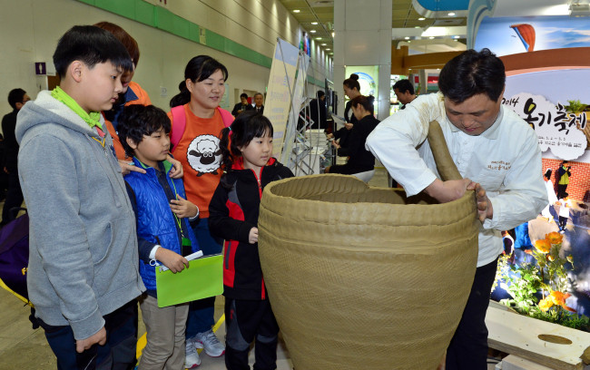 Visitors watch an artisan make a Korean earthenware pot called “onggi” at the Korea Travel Expo at Coex in Samseong-dong, Seoul on Thursday. The expo is one of the biggest travel fairs in the country offering Korean tour information and products.   Lee Sang-sub/The Korea Herald