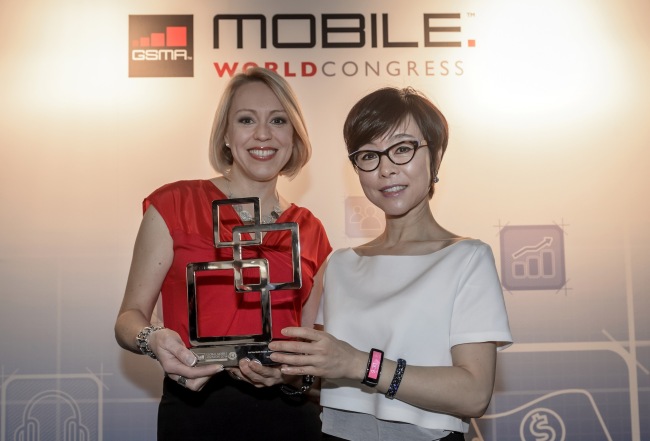 Lee Young-hee, executive vice president of Samsung Electronics’ mobile business unit, and Sasha Twining, a presenter for Mobile World Live TV, pose with a trophy that the Korean tech giant’s Gear Fit won for best mobile device at Mobile World Congress 2014 in Barcelona on Thursday.   Samsung Electronics