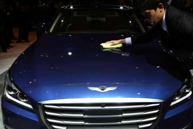An event staff member wipes the hood of Hyundai Motor Co.’s new Genesis sedan during the unveiling ceremony in Seoul on Nov. 26. Bloomberg