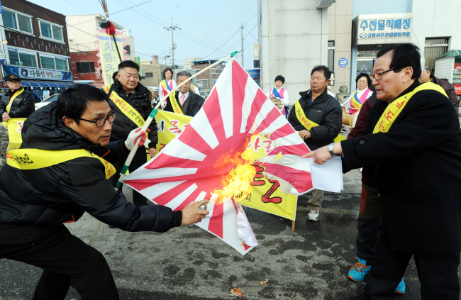 Protestors set a Japanese rising sun flag alight during a protest over the disputed Dokdo Islets in Gangneung City, Gangwon Province, on Feb. 21. Foreign embassies unintentionally stepped into the controversy and became targets of criticism here by using country domains of Google Maps with the place names “Liancourt Rocks” and “Sea of Japan.”   Yonhap