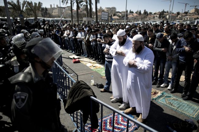 Israeli Border Police stand guard as Palestinians pray in front of a police barrier outside the Damascus Gate in Jerusalem’s Old City on Feb. 28.   EPA-Yonhap