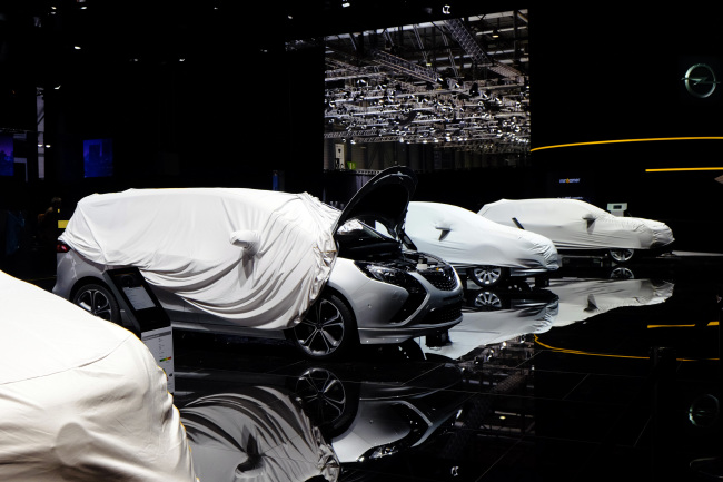 Protective covers sit over Opel automobiles during preparations ahead of the 84th Geneva International Motor Show in Geneva, Switzerland, Sunday.   Bloomberg