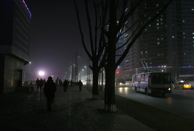 North Koreans walk on a street at a residential complex which is lit at night in Pyongyang,.  (AP-Yonhap)