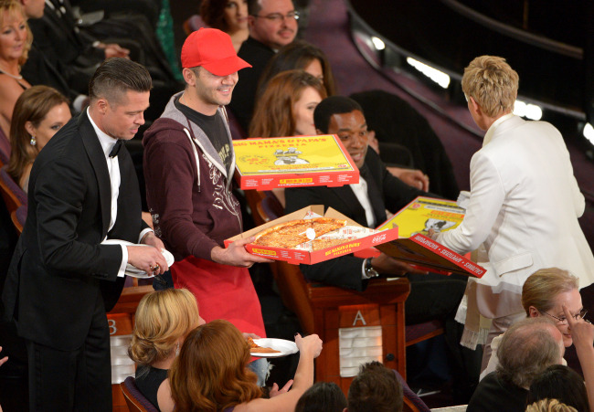 Brad Pitt (left) and Ellen DeGeneres (right) pass out pizza to the audience during the Oscars at the Dolby Theatre in Los Angeles on Sunday.   AP-Yonhap
