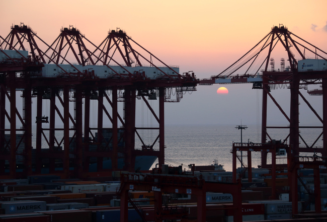 The sun sets behind cranes at the Yangshan Deep Water Port in Shanghai.   Bloomberg
