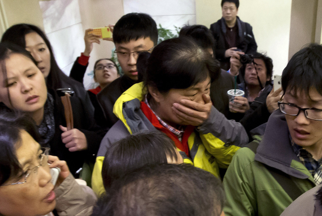 A woman surrounded by media covers her mouth on her arrival at a hotel reserved for relatives or friends of passengers aboard a missing airplane in Beijing on Saturday.   AP-Yonhap
