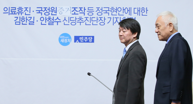 Reps. Ahn Cheol-soo (left) and Kim Han-gil head to their seats before their joint press conference at the National Assembly in Seoul on Sunday.   Yonhap
