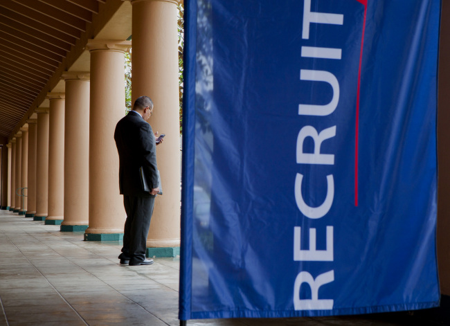 A job seeker checks his mobile phone outside of a job fair in San Diego, California, Feb. 27.   Bloomberg