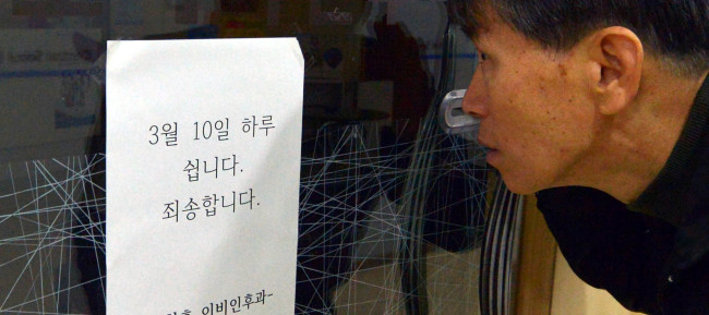 A citizen looks at a notification of a one-day closure at a Seoul clinic on Monday.   Kim Myung-sub/The Korea Herald