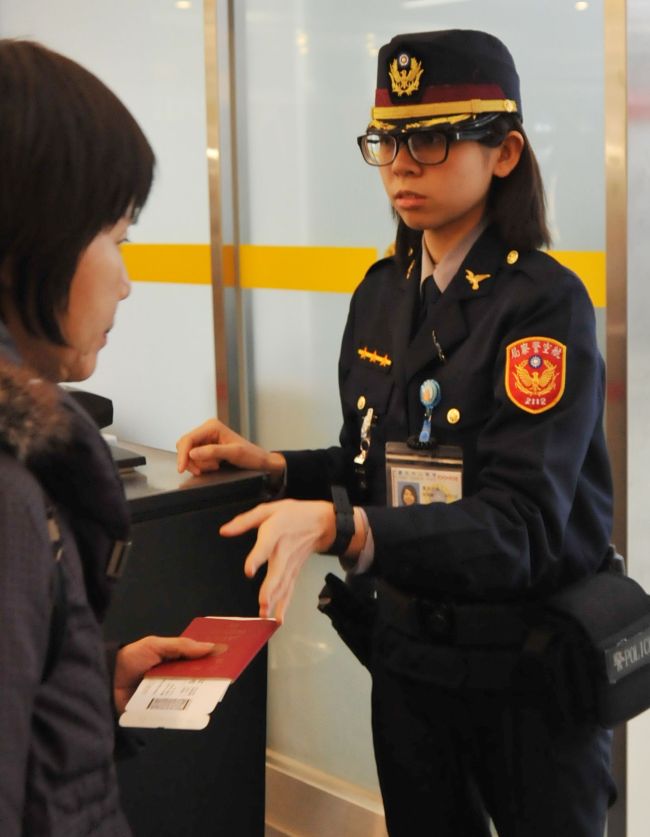 An airport security officer checks a passenger’s passport and boarding pass at the Taipei Songshan Airport on Monday.   AFP-Yonhap