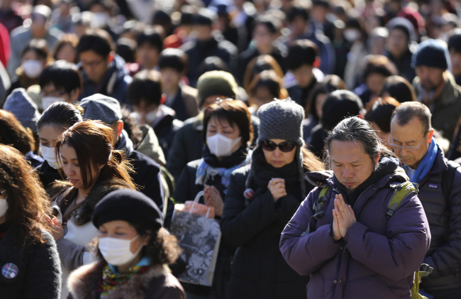 People observe a moment of silence at 2:46 p.m. in Tokyo Tuesday, March 11, 2014, three years after a massive earthquake and tsunami struck northeastern Japan. Japan marked the third anniversary on Tuesday of a devastating disasters that left nearly 19,000 people dead or missing. (AP-Yonhap)