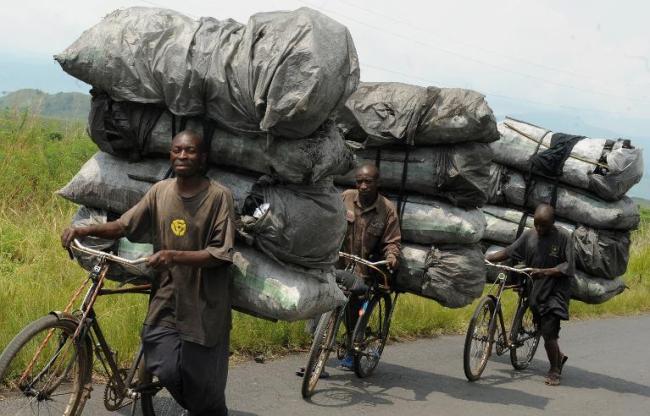 Congolese charcoal dealers push their bicycles up the hill as they transport their produce to the market in Sake, North Kivu.   AFP