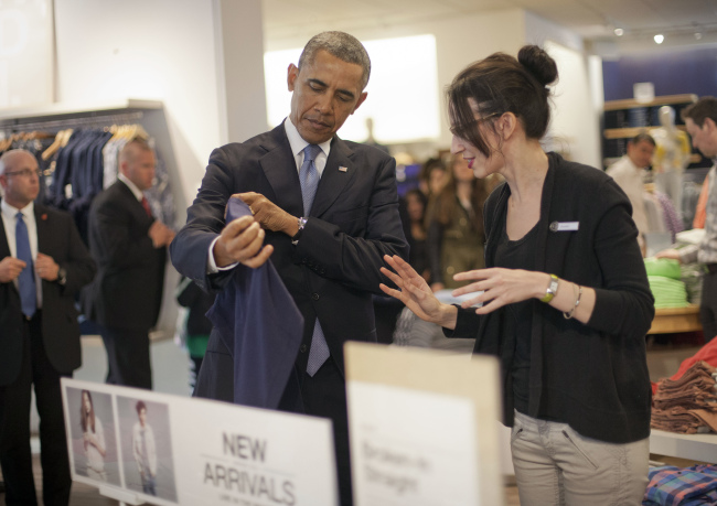 President Barack Obama (left) with the help of store employee Susan Panariello shops at the GAP clothing store in Manhattan during his unannounced visit in New York on Tuesday.   AP-Yonhap