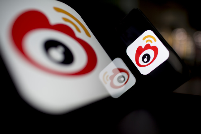 The logo of Sina Corp.’s Sina Weibo microblog service is displayed on an Apple Inc. iPad and iPhone in Hong Kong.  Bloomberg