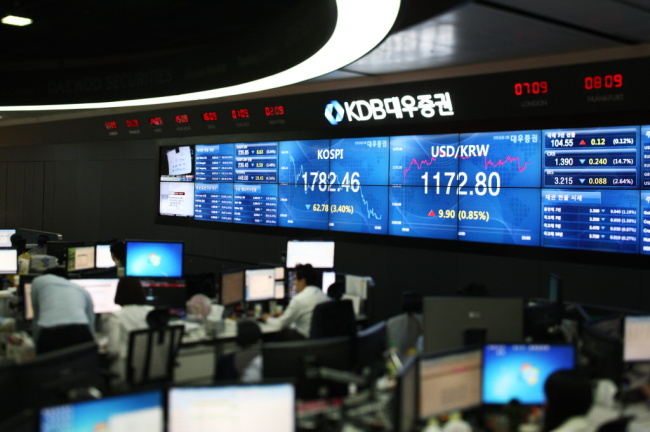 KDB Daewoo Securities employees work in front of a monitor displaying the Korea Composite Stock Price Index (left) and the Korean won to USD exchange rate in the trading room of the company’s headquarters in Yeouido, Seoul.   Bloomberg