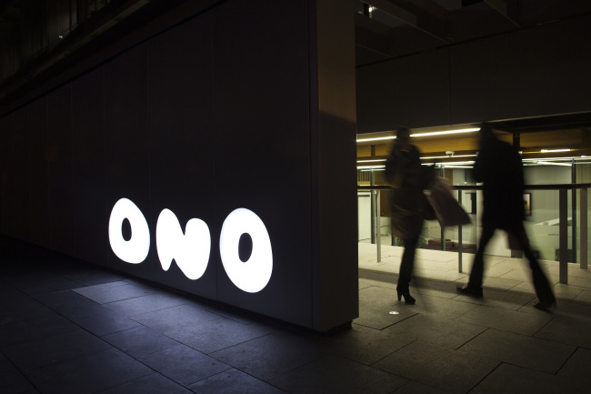 Visitors pass a logo outside the headquarters of Grupo Corporativo Ono SA in Pozuelo de Alarcon, Spain.   Bloomberg