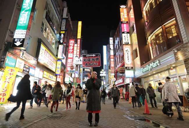 An employee holds a sign for an “okonomiyaki” restaurant in the Shibuya district of Tokyo.  Bloomberg
