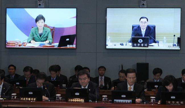 President Park Geun-hye presides over a weekly Cabinet meeting in a video conference room at Cheong Wa Dae that simultaneously connects Prime Minister Chung Hong-won (on right screen) and ministers in Sejong City on Tuesday. (Park Hyun-koo/The Korea Herald)
