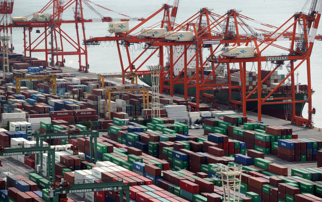 A container ship sits berthed next to gantry cranes at a shipping terminal in Tokyo.   Bloomberg