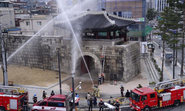 Fire fighters and officials from Seoul’s Jung-gu Office participate in an exercise to improve responses to fires at cultural assets at Gwanghuimun Gate in central Seoul on Wednesday.   Park Hae-mook/The Korea Herald