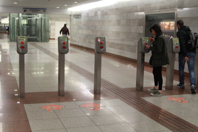 Passengers go through the ticket barriers in a subway station in Greece.   LG CNS