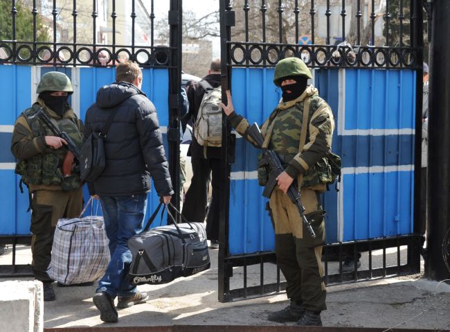 Ukrainian officers leave as Russian soldiers patrol at the Ukrainian navy headquarters in the Crimean city of Sevastopol on Wednesday.   AFP-Yonhap