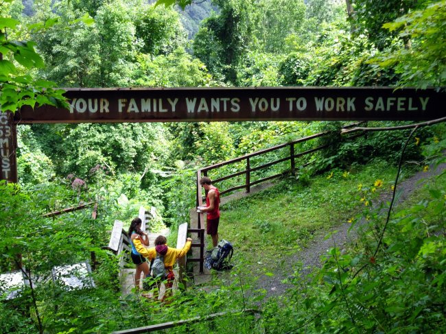 Climbers rest under a steel beam with a suggestion to former coal miners at Kaymoor mines in West Virginia’s New River Gorge.   Akron Beacon Journal