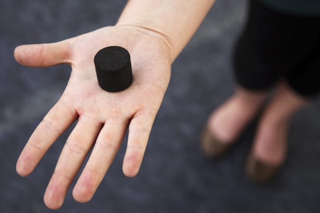 An exhibitor displays a Biochar, a charcoal-like product made from human waste that can be used as cooking fuel or fertilizer.   AP-Yonhap