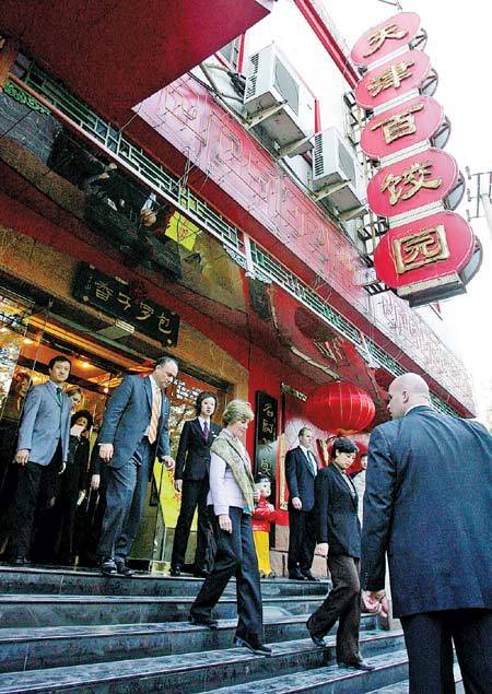 Former U.S. first lady Laura Bush (center) walks out of the Tianjin Baijiaoyuan restaurant, where she ate lunch in Beijing in November 2005.   China Daily