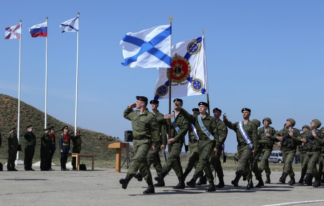 Russian Defense Minister Sergei Shoigu (third from left) looks at Russian marines as they march with the flags of the Russian Navy and Sevastopol at a military base in Sevastopol, Crimea, Monday.   AP-Yonhap