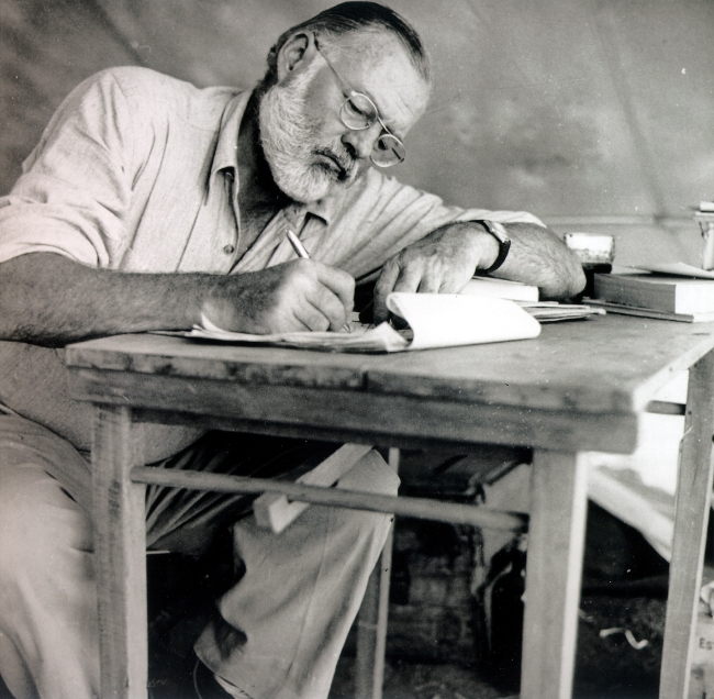 Ernest Hemingway writing at a desk while on safari in 1953. MCT