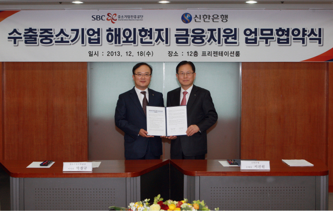 Seo Jin-won (right), Shinhan Bank president, poses with Park Cheol-kyu, president of the Small and Medium Business Corporation after signing an agreement to provide financial services to SMEs operating overseas at SBC’s headquarters in Seoul in December 2013.   Shinhan Bank.