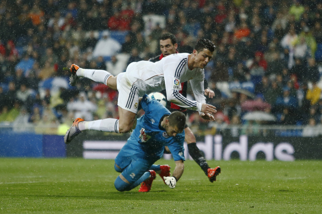 Real’s Cristiano Ronaldo (top) clashes with Rayo Vallecano goalkeeper Ruben on Saturday.   AP-Yonhap