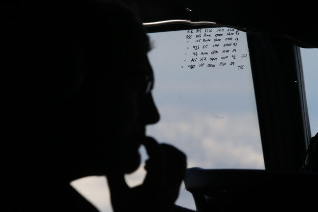 A crew member is silhouetted aboard a Royal New Zealand Air Force P-3K2 Orion aircraft alongside handwritten notes of other search craft in the area as it searches for the missing Malaysia Airlines Flight MH370 over the southern Indian Ocean on Saturday.   AP-Yonhap